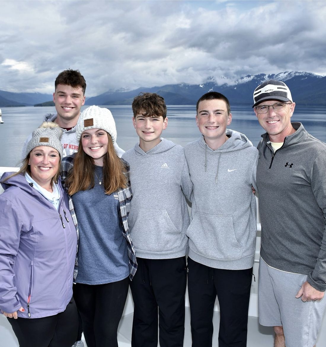 ’Chelle with her family on a cruise ship deck, with Alaska mountains and water behind